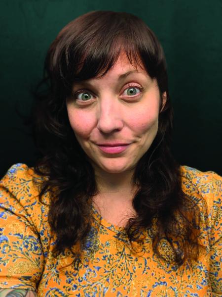 Colleen AF Venable photo. A white woman with shoulder length curly brown hair wearing a yellow and blue floral shirt. 