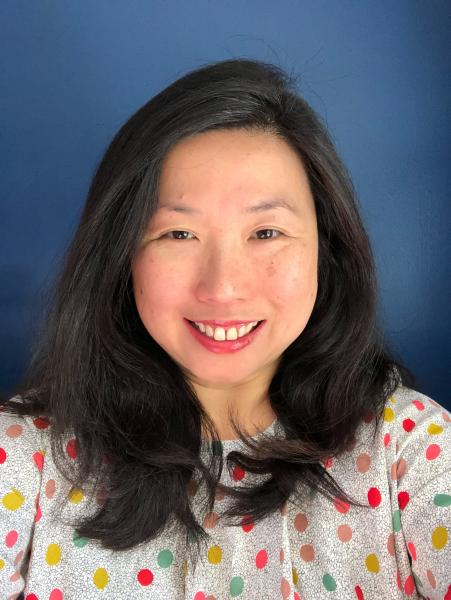 Patricia Tanumihardja author photo provided. An Asian woman with shoulder length black straight hair wearing a red, green, and yellow polka dot blouse smiling directly at the camera.
